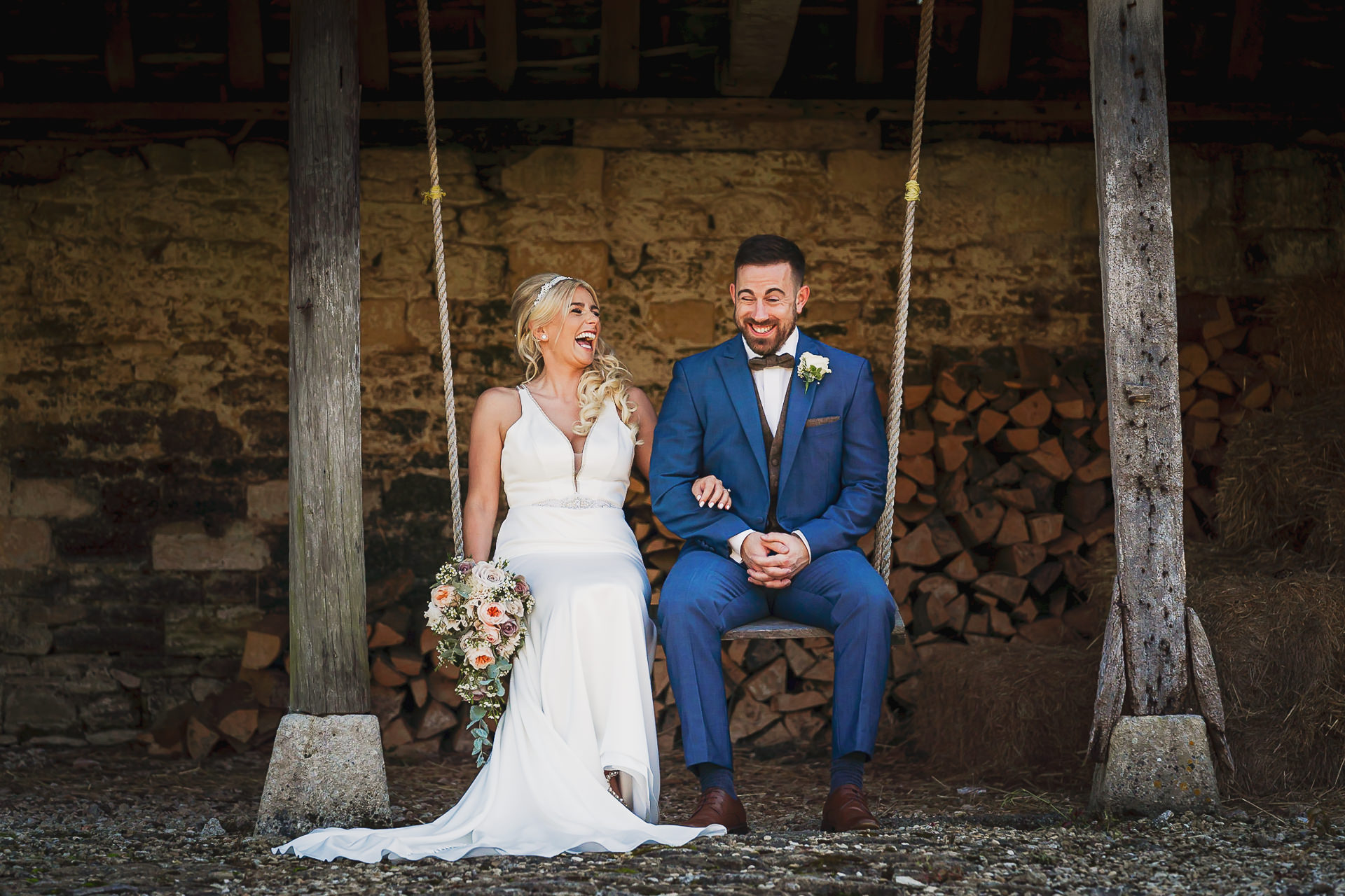 Bristol wedding photographer captures the love between a bride and groom sitting on a swing in a barn.