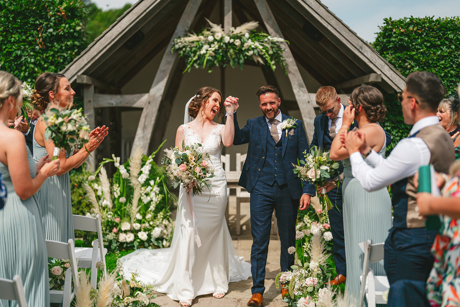 A bride and groom have their Kingscote barn wedding ceremony as they walk down the aisle.