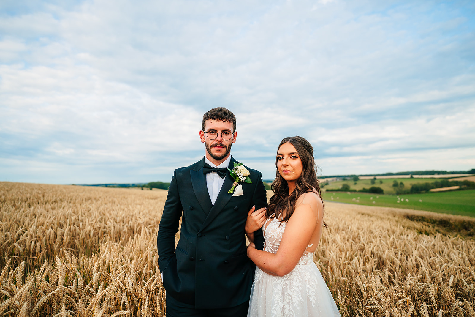 A bride and groom standing in the Kingcote Barn, surrounded by a wheat field.